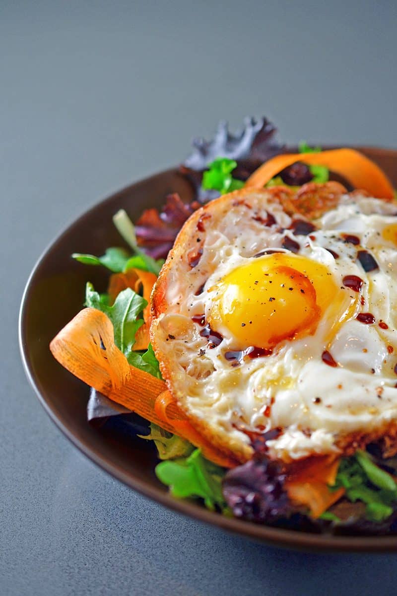 Close up of Sunnyside Salad, crispy fried eggs on top of salad greens.