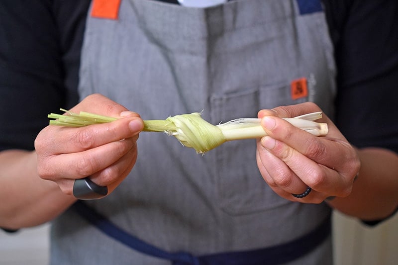 A smashed stalk of lemongrass tied into a knot to throw into a pot of healthy Tom Kha Gai