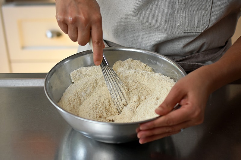 Whisking the dry ingredients in a silver mixing bowl for paleo and gluten free apple Bundt Cake