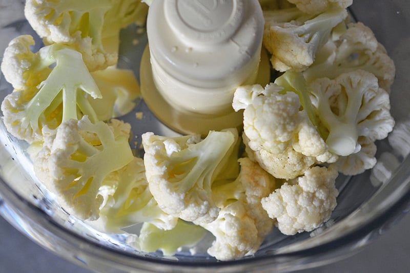 Overhead shot of cauliflower florets in a food processor
