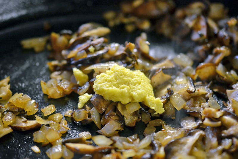 Adding the minced ginger to the frying pan with the mushrooms and onions.