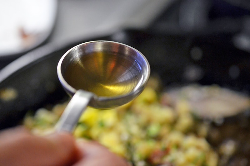 Adding a spoonful of fish sauce to flavor Asian Cauliflower Fried “Rice” 