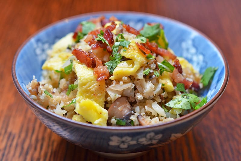 A closeup shot of Asian Cauliflower Fried Rice in a blue and white bowl