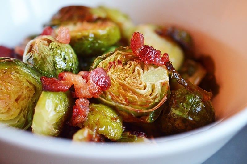 A side view of Roasted Brussels Sprouts and Bacon in a white bowl