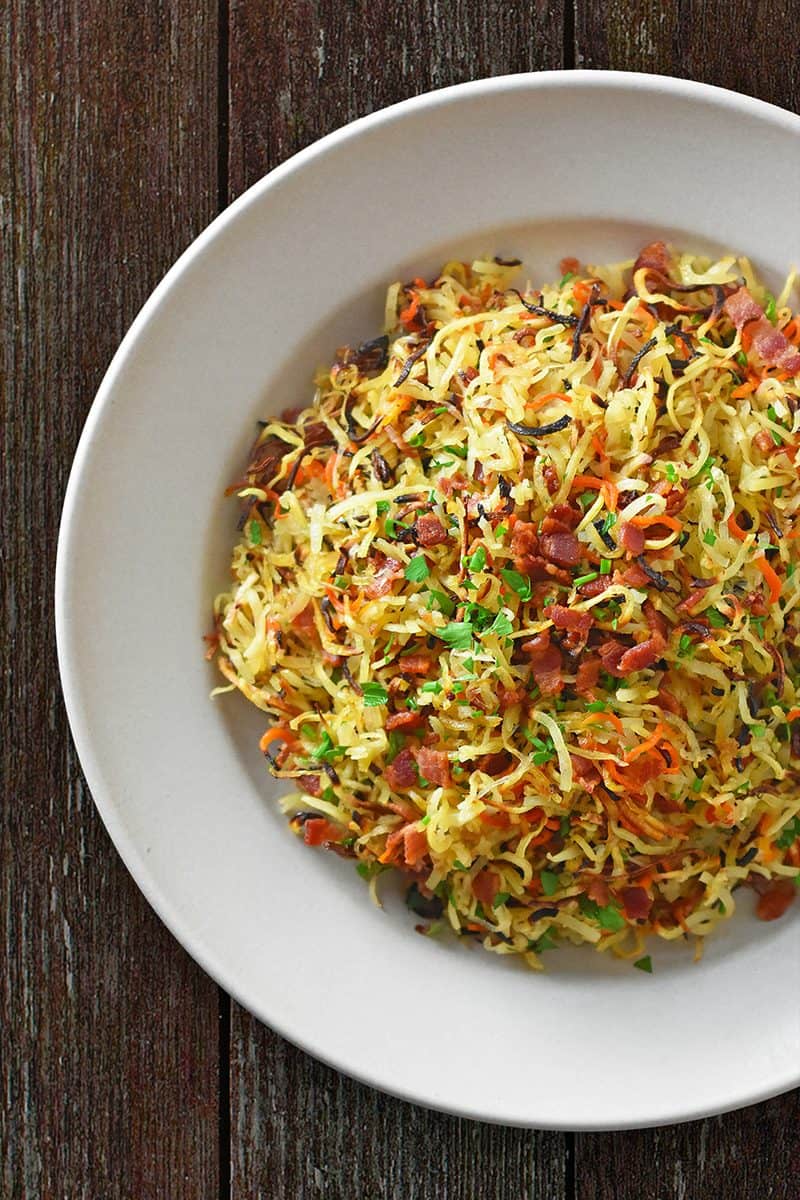 An overhead shot of a plate of Crispy Swoodles with Bacon, a Whole30 and paleo side dish made with spiraled sweet potatoes