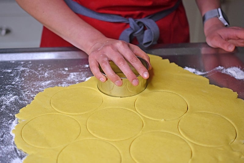 Using a biscuit cutter to cut out circles in the flattened dough