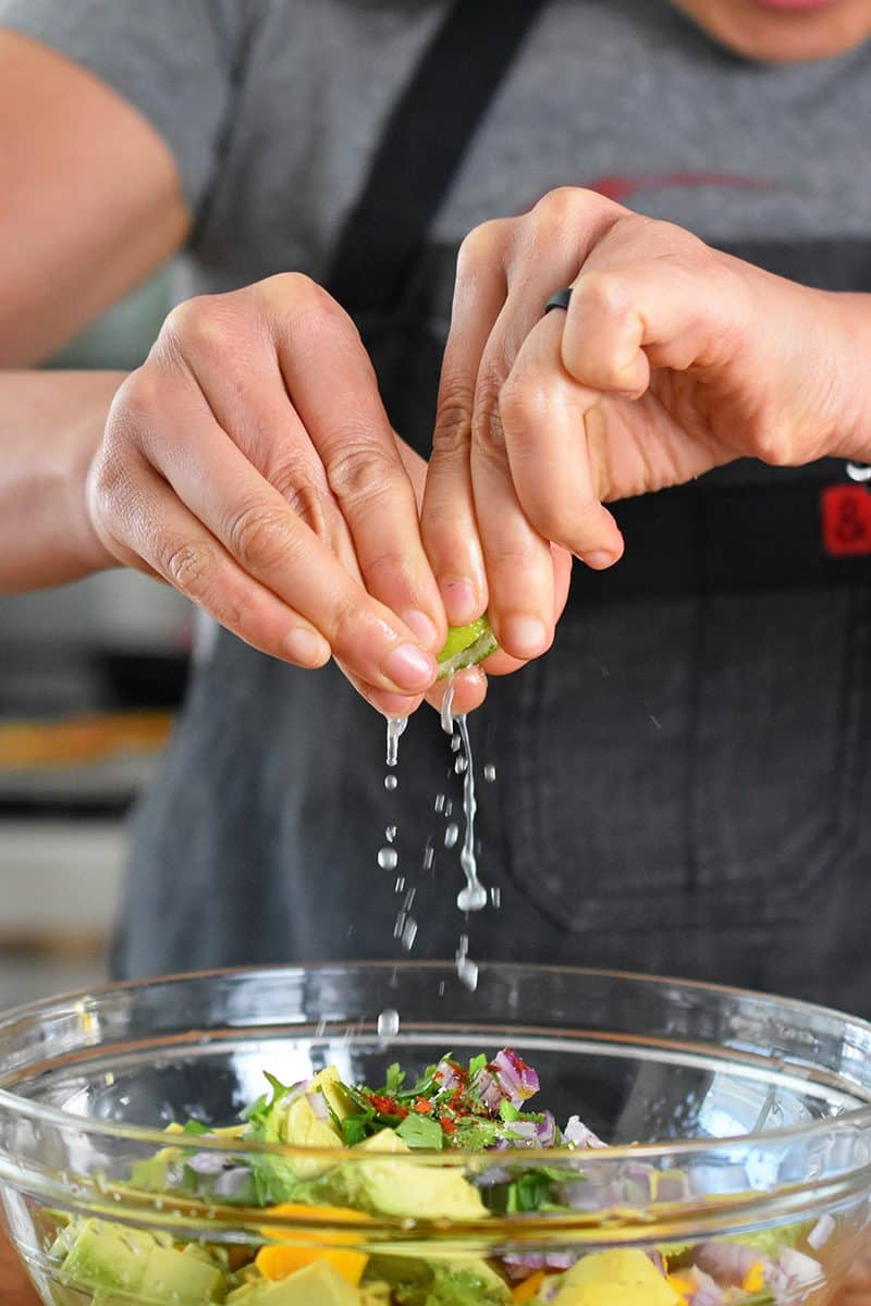 Squeezing a slice of lime over a bowl for the paleo and Whole30 recipe of fried green plantains and mango avocado salsa.