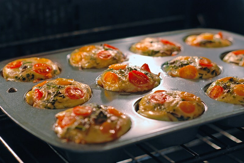 Prosciutto-Wrapped Mini Frittata Egg Muffins baking in the oven.
