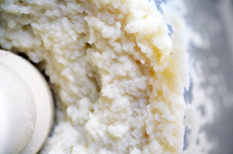 An overhead shot of garlic cauliflower mashed potatoes in an open food processor.