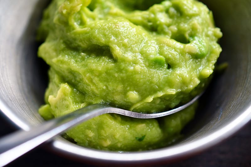 Top view of guacamole in a bowl with a serving spoon.