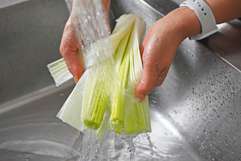 Someone rinsing sliced up leeks for Instant Pot Curried Cream of Broccoli Soup 