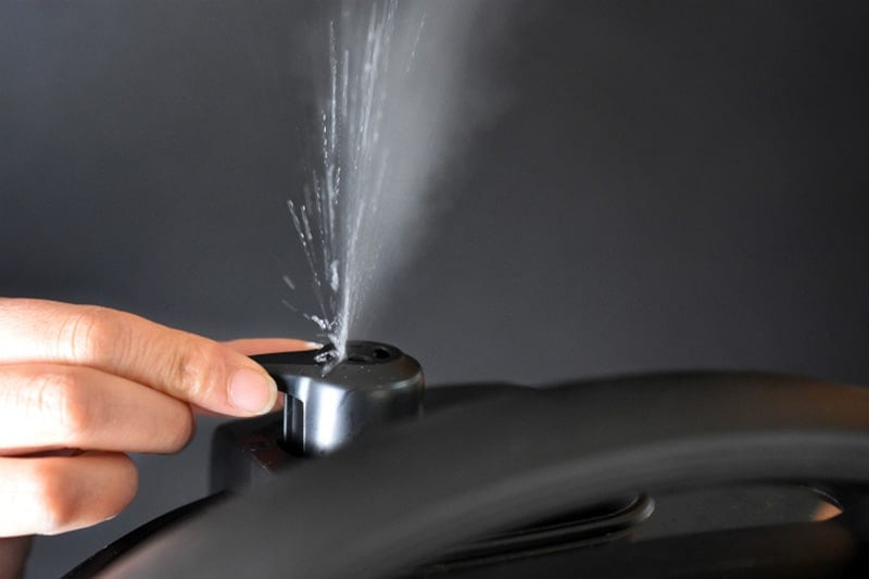Someone manually releasing pressure from an Instant Pot and steam escaping from the valve.