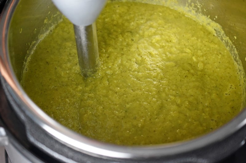 An immersion blender is pureeing Instant Pot Curried Cream of Broccoli Soup until smooth