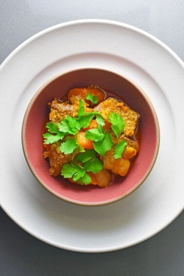 An overhead shot of a bowl of Instant Pot Thai Beef Curry topped with cilantro leaves.