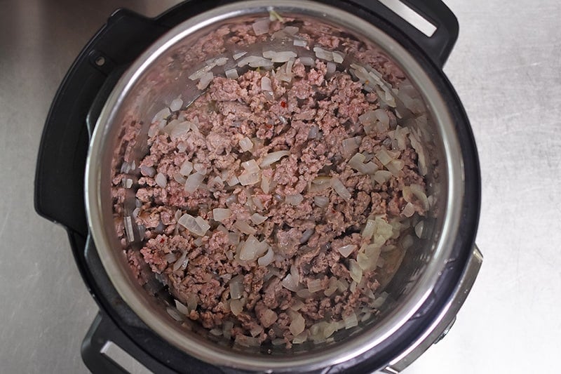 An overhead shot of cooked Italian sausage and onions in an open Instant Pot.