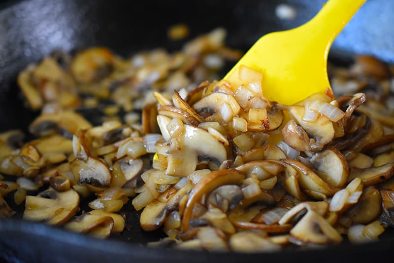 A closeup of the cooked mushrooms and onions in a cast iron skillet.