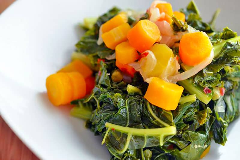 A closeup shot of a white plate filled with Pressure Cooker Braised Kale and Carrots 