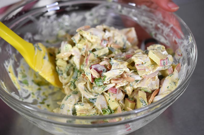 The ingredients for curry chicken salad getting mixed in a bowl.