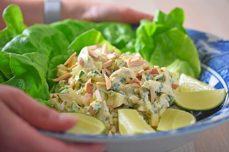 Someone holding a bowl of madras curry chicken salad.