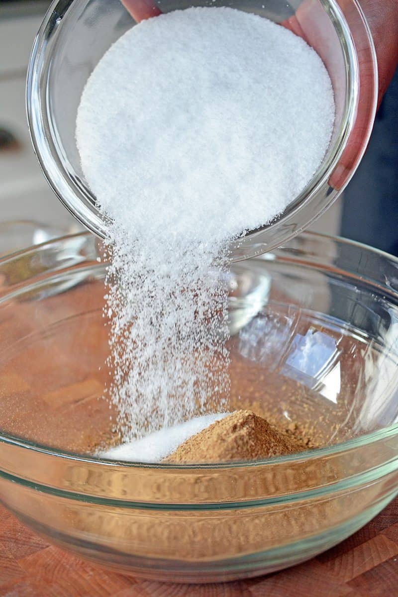Pouring a large bowl of salt into a bowl of powdered porcini mushrooms. 