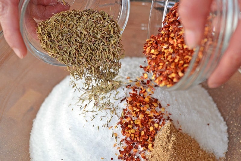 Adding dried thyme and red crushed peppers to the bowl of salt and porcini mushrooms. 