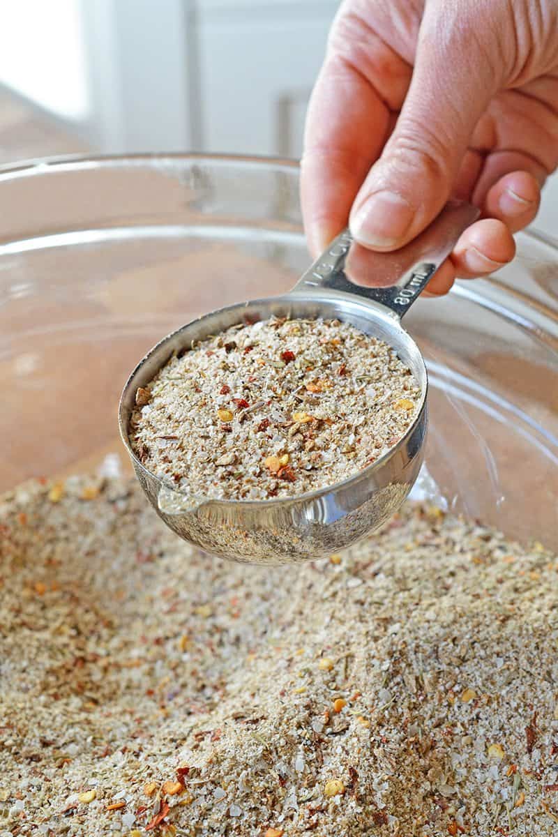Scooping Magic Mushroom Powder out of a bowl with a measuring cup.