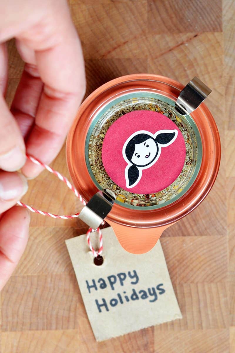 An overhead shot of a jar of homemade Magic Mushroom Powder with a happy holidays tag tied on.