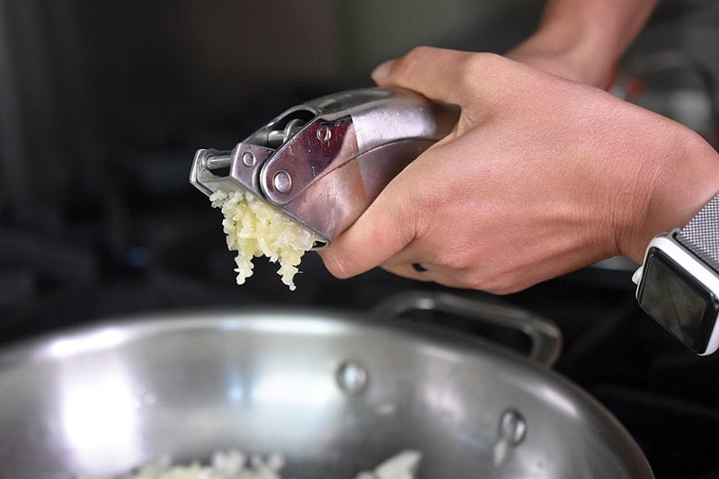 Adding minced garlic to the onions in the pan for low carb Mexican Cauliflower rice