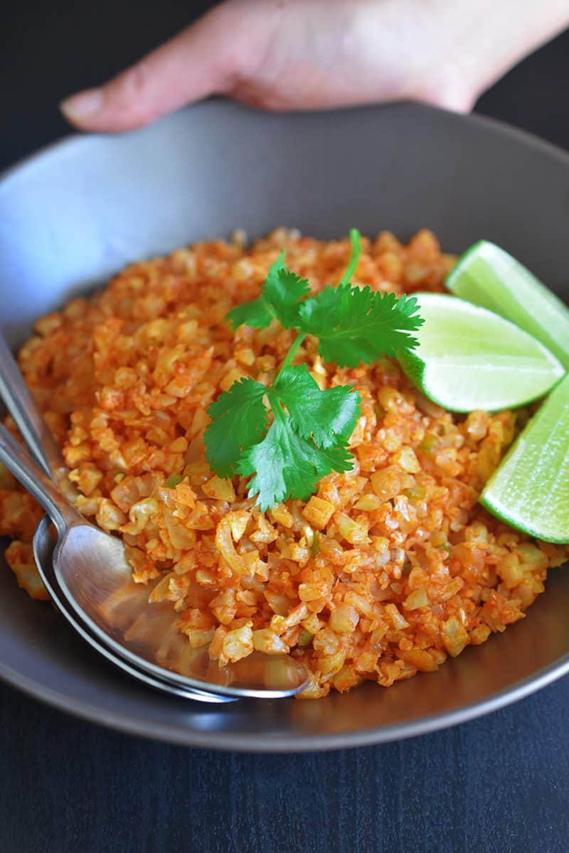 Whole30 and paleo Mexican cauliflower fried rice in a bowl topped with fresh cilantro and limes.