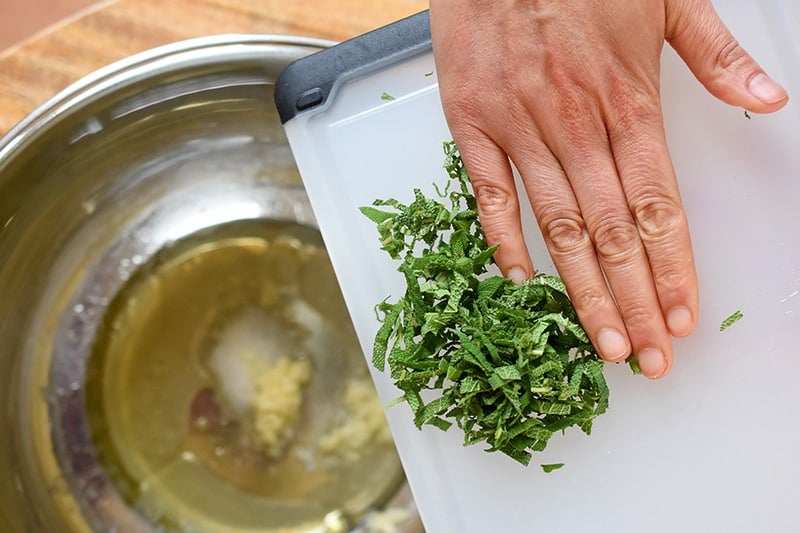 Adding the marinade ingredients for Sheet Pan Pork Chop Supper to a large metal mixing bowl.