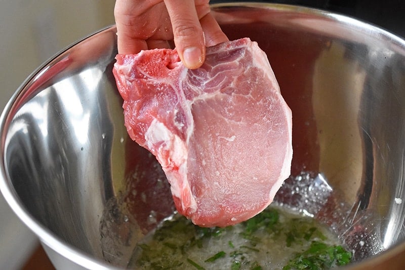 Adding the pork chops to the marinade.