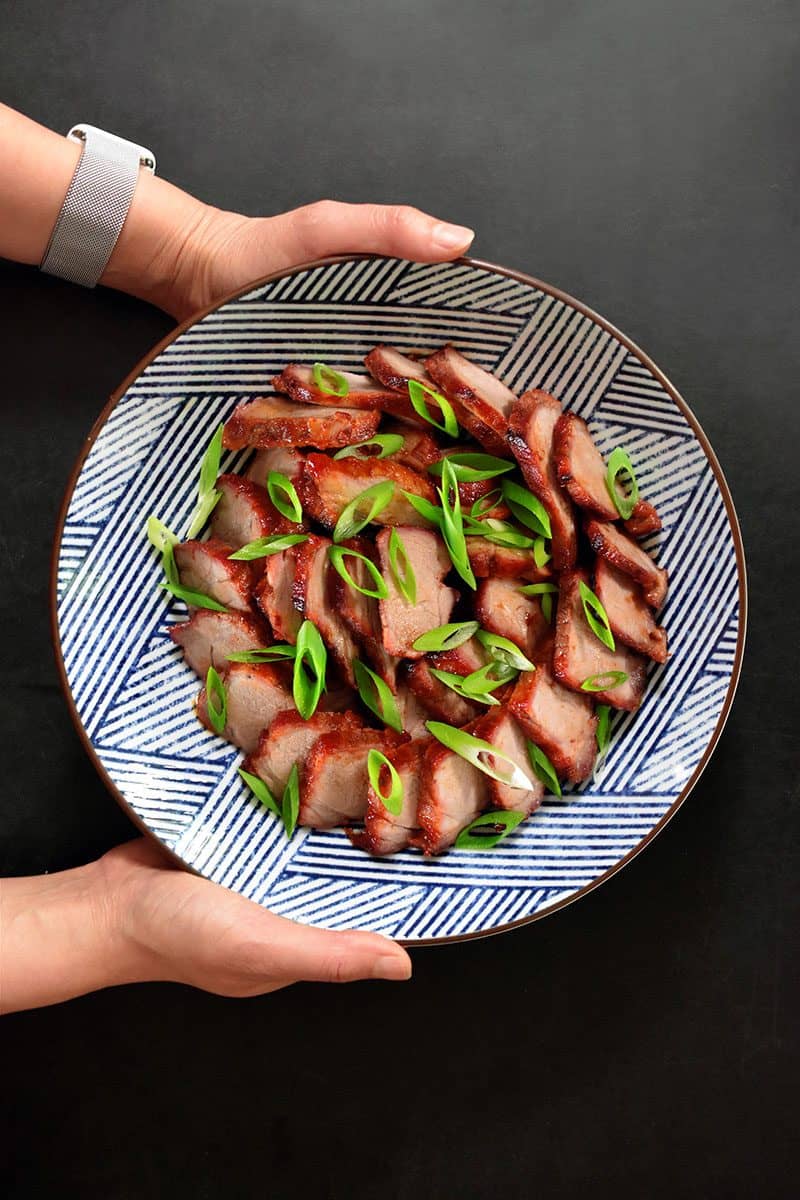 An overhead shot of Paleo Char Siu (Chinese BBQ Pork) in a blue and white Japanese bowl topped with sliced scallions.