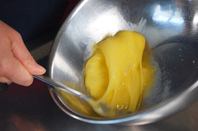 Someone beating eggs in a metal bowl with a fork.