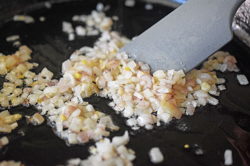 Stir-frying the diced shallots until softened. 