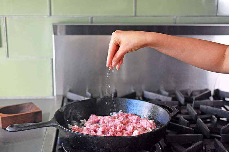 Seasoning the ground pork with a sprinkle of salt. 