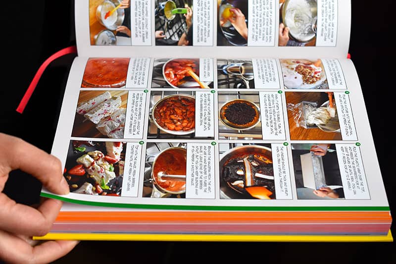 A hand is flipping open the pages of Ready or Not! cookbook by Michelle Tam and Henry Fong