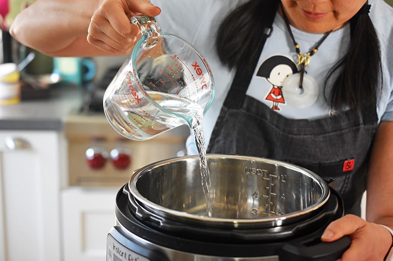 Someone pouring water into an instant pot for instant pot beets.