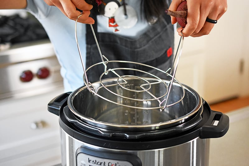 Someone inserting a metal rack into an instant pot.