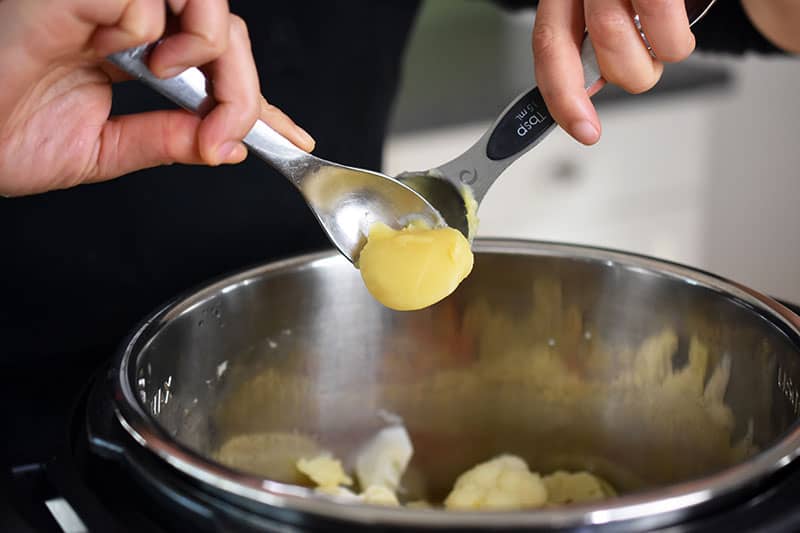Someone adding ghee into the metal insert of an Instant pot.