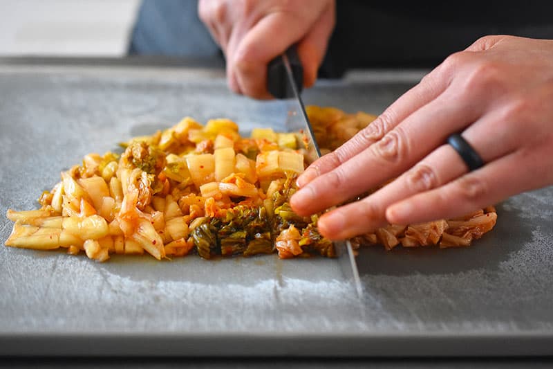 Someone chopping kimchi on a cutting board.