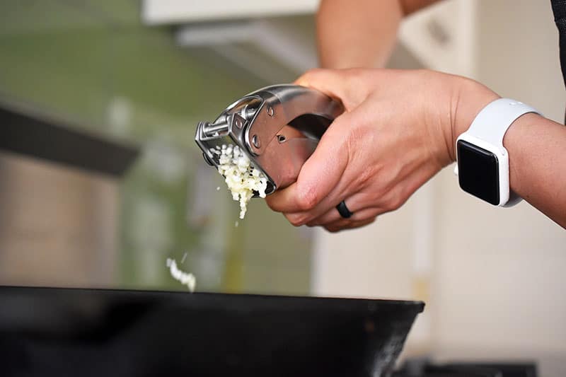 Someone adding garlic into a pan.