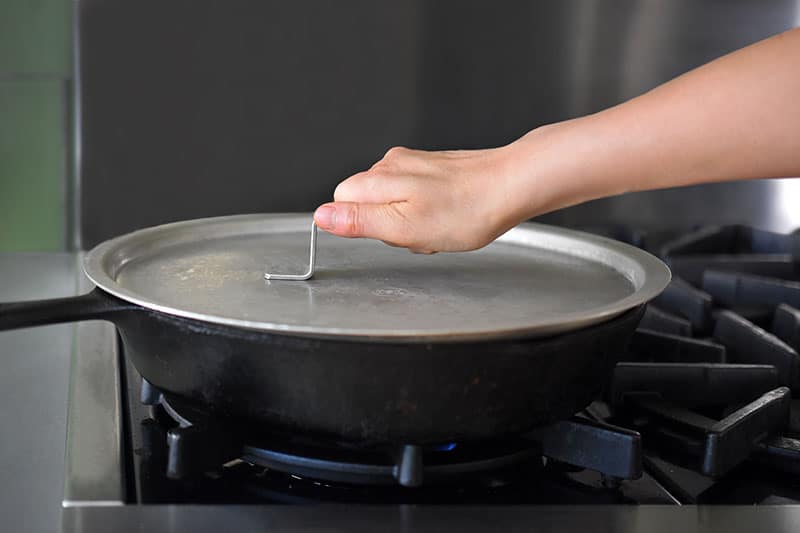 Someone putting a cover on top of a pan.
