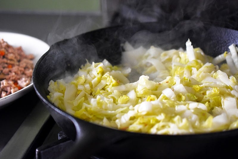 Sautéing sliced napa cabbage in a cast iron skillet.
