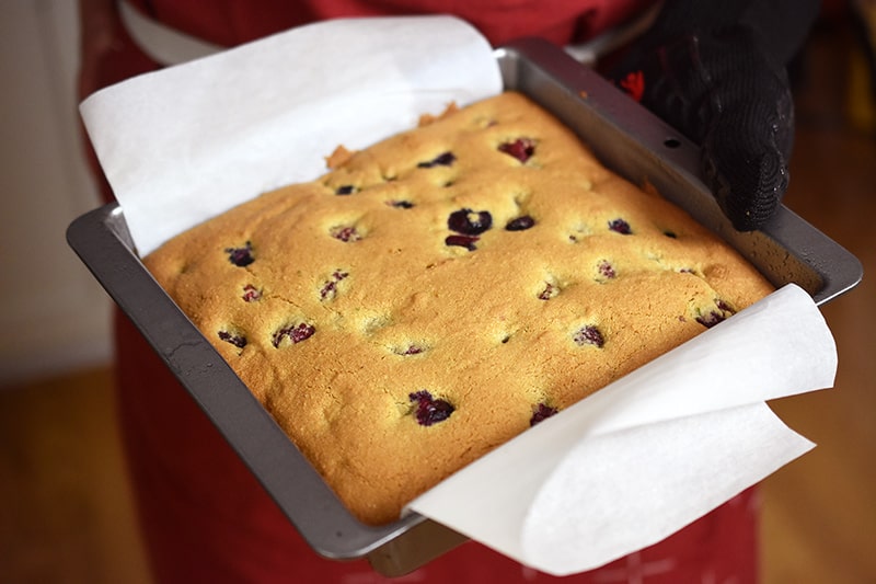A golden brown berry snack cake is being removed out of the oven.