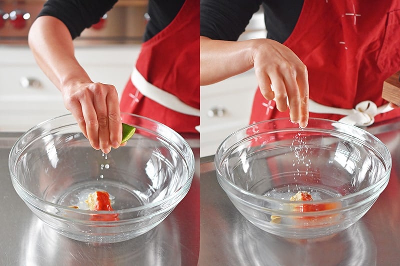 Someone squeezing lime and adding salt to a bowl for the spicy Thai dressing.