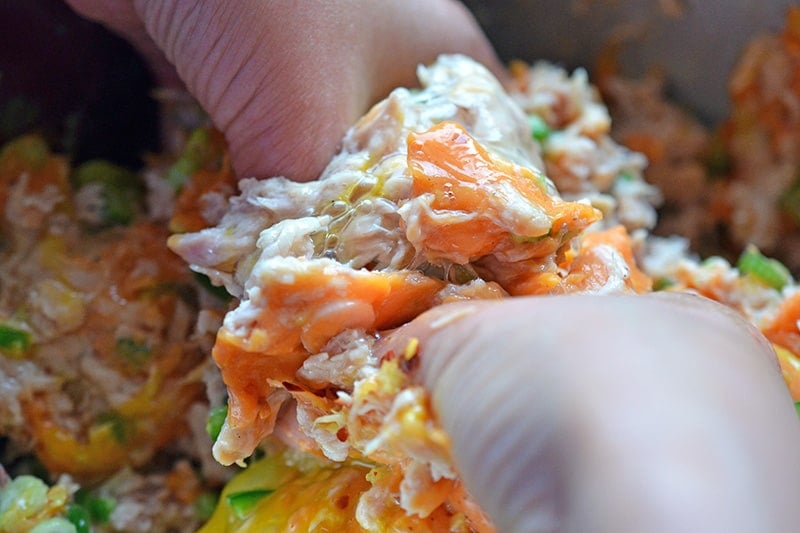 Someone mixing together the spicy tuna cake mixture with their hands.