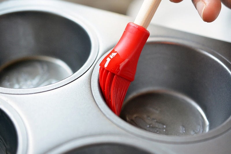 Brushing grease in the muffin tins.