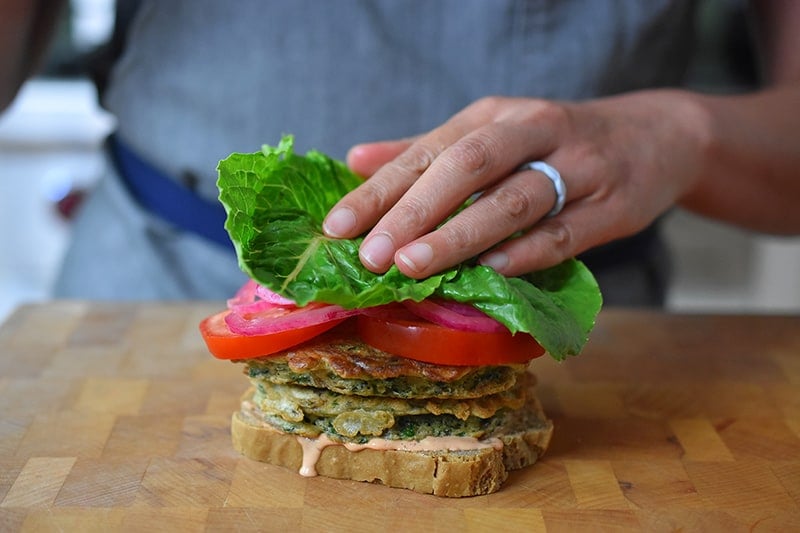 Adding a piece of lettuce on a paleo St. Paul sandwich.