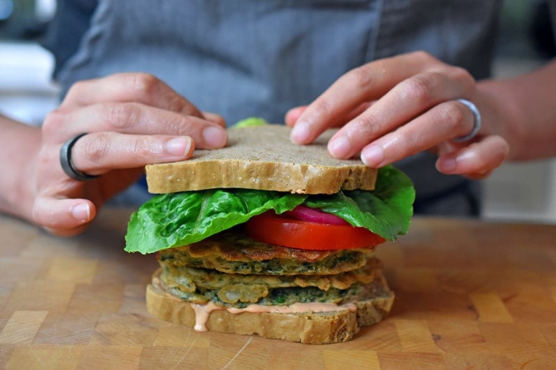 Two hands topping a paleo and gluten free St. Paul sandwich with a slice of grain-free bread.