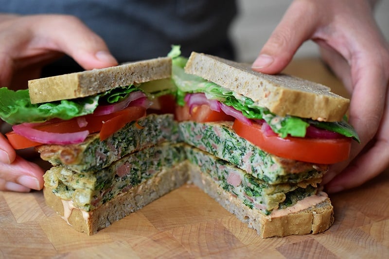 Someone holding two halves of a St. Paul sandwich with gluten-free and paleo-friendly ingredients.